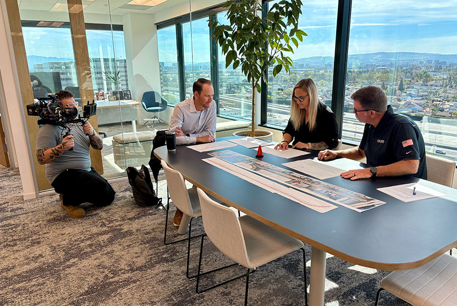 Videographer capturing team meeting with three employees around a conference table
